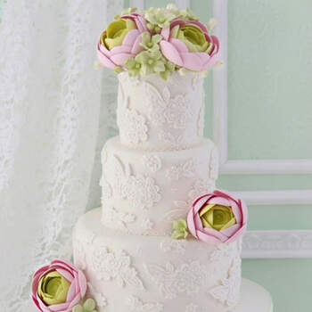 Un diseño romántico y contemporáneo con aplicaciones de encaje en azúcar y bouquet de ranúnculos y hortensias de azúcar.