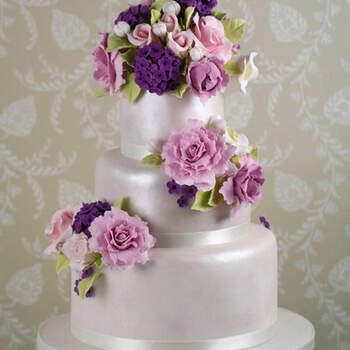 Tarta cubierta con fondant perlado blanco y bouquets de lilas rosas y peonías realizadas a mano en azúcar.
