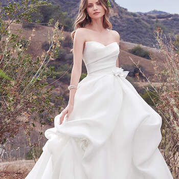 This simple yet glamorous Cameo Organza ballgown features a softly pleated bodice and voluminous pickups in the skirt. A distinctive sweetheart neckline and handmade 3D floral motif, accented with Swarovski crystals, at the hip and skirt add unique romance to this look. Finished with zipper closure.
