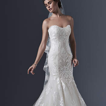 Timeless romance is updated in this classic mermaid silhouette. Striking bold patterned lace on tulle cascades down the bodice and traces the hemline. A layer of glitter tulle adds a subtle hint of sparkle. Finished with delicate scoop neckline and crystal buttons over zipper and inner corset closure.
<img height='0' width='0' alt='' src='http://ads.zankyou.com/mn8v' />