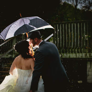 Preciosa imagen de los novios besándose bajo el paraguas. Foto: Michael Steingarden. 