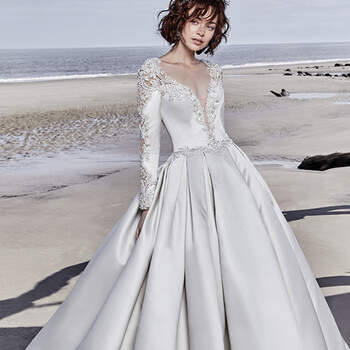 This breathtaking Carlo Satin wedding dress features long sleeves accented in exquisite illusion lace details and beading. Swarovski crystals adorn the waistline above a billowing, pleated ballgown skirt featuring pockets. Complete with illusion plunging V-neckline and scoop back. Covered and crystal buttons trail from zipper to hem.

<a href="https://www.maggiesottero.com/sottero-and-midgley/brennon/11523">Sottero and Midgley</a>