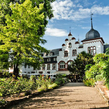 Hotel Kronenschlösschen: Das luxuriöse Kronenschlösschen ist das Hochzeits-Hotel par excellence. Im romantischen Dörfchen Hattenheim, – mit seinen Fachwerkhäusern, alten Straßen und Gassen, mit der historischen Burg und der Barockkirche St. Vincent einer der schönsten Orte im Rheingau – liegt das Hotel Kronenschlösschen inmitten eines Privatparks mit Blick auf den Rhein. 