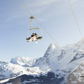 Wedding couple on chairlift reaching their wedding ceremony in winter with snow and mountain in Mürren