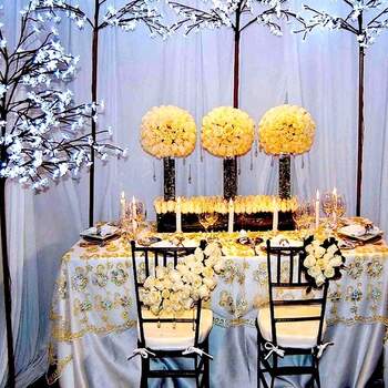 Centros de mesa con rosas amarillo claro, velas, rosas blancas para las sillas, mantel azul aguamarina con pedrería y velas. Es un tipo de decoración muy elegante que está de moda. 