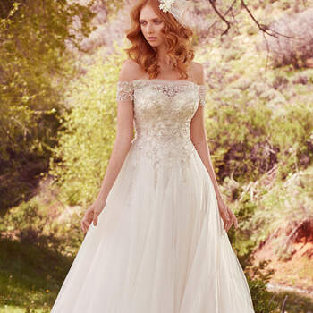 A layer of ruched tulle atop the bodice of this regal ballgown creates illusion off-the-shoulder sleeves, illusion sweetheart neckline, and illusion back, all adorned with lace appliqués and exquisite Swarovski crystal beading. Complete with a breathtaking tulle skirt. Finished with crystal buttons over zipper closure. 
<a href="https://www.maggiesottero.com/maggie-sottero/iris/10107?utm_source=mywedding.com&amp;utm_campaign=spring17&amp;utm_medium=gallery" target="_blank">Maggie Sottero</a>