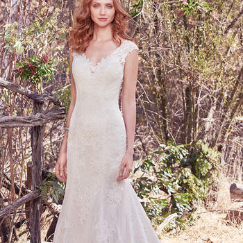 Vestido de novia ajustado con apliques de encaje y cuentas. Los apliques de encaje adornan las mangas de ilusión, el escote corazón y una espalda descubierta. Terminado con botones cubiertos sobre cierre de cremallera.
