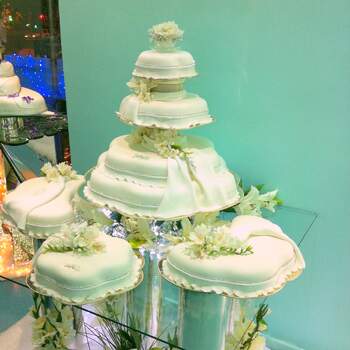 Composición de cuatro tartas nupciales decoradas con flores sobre mesa de cristal