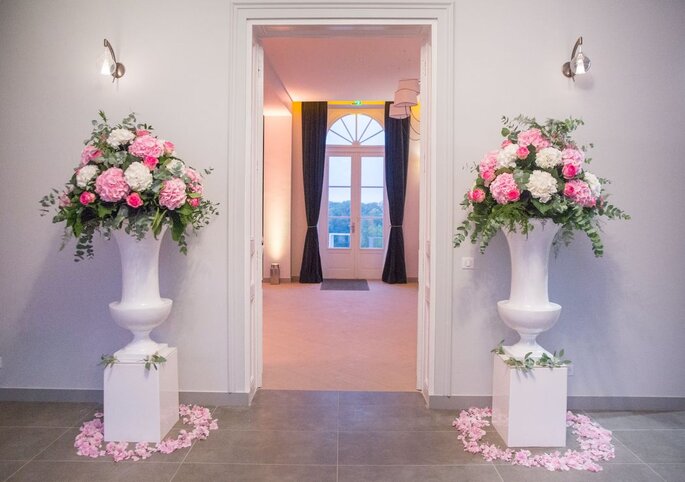 Le Domaine des Cormellas, deux grands vases fleuris avec des fleurs roses et blanche à l'entrée de la salle de réception
