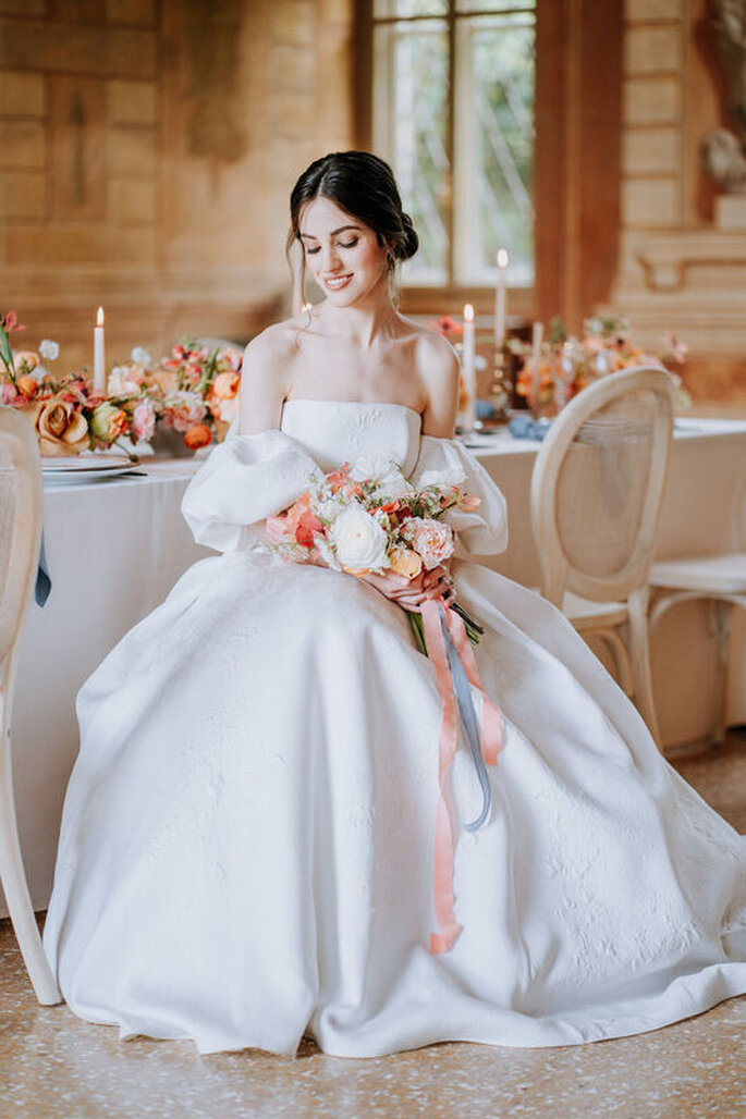 sposa seduta davanti al tavolo imbandito, bouquet in mano