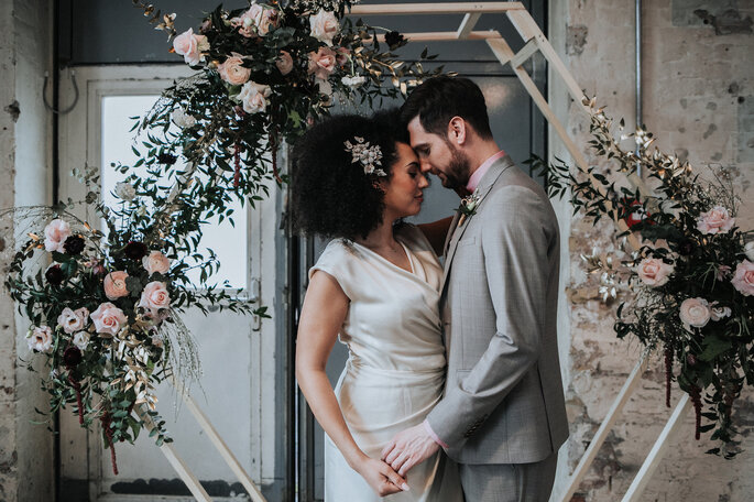 Das Brautpaar steht unter dem mit Blumen dekorierten Traubogen, organisiert von Freakin' Fine Weddings.