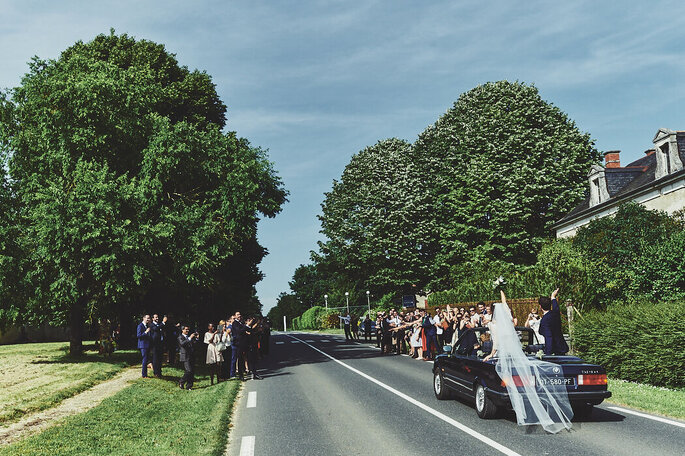 Les mariés en voiture sous les applaudissements de leurs invités