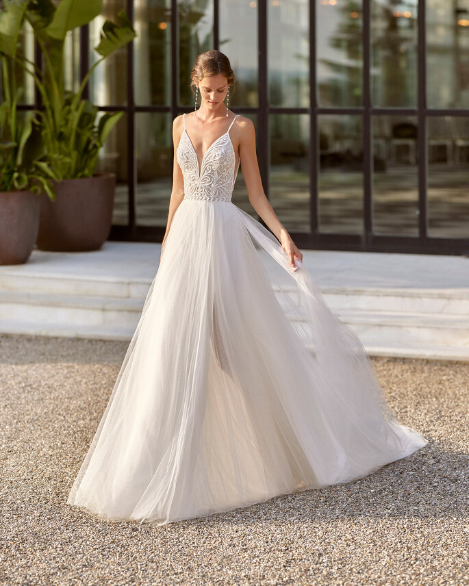 vestido de novia con escote v sobre corpiño de tirantes delgados y falda voluminosa de tul
