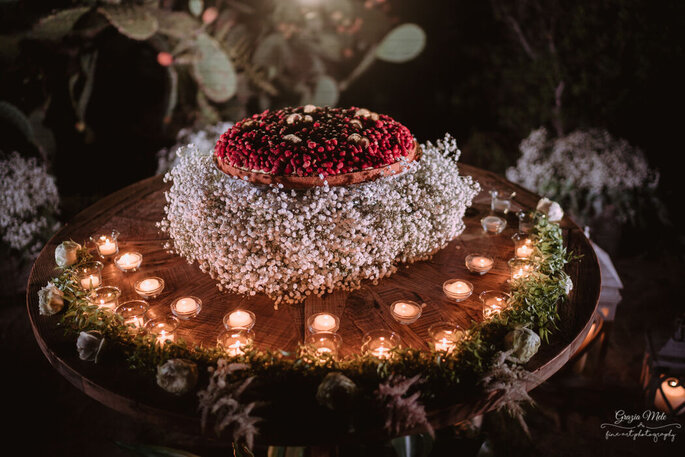 wedding cake a un piano, con candele e frutti rossi