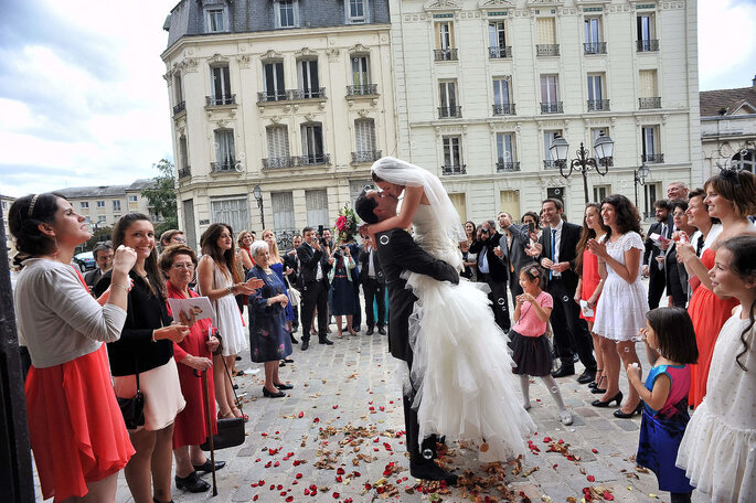 Un couple de mariés s'embrassent devant l'église et la foule 