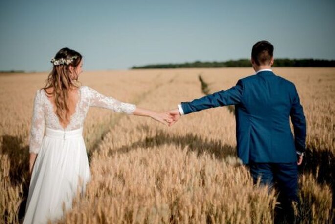 les mariés se tiennent la main dans les champs de blé