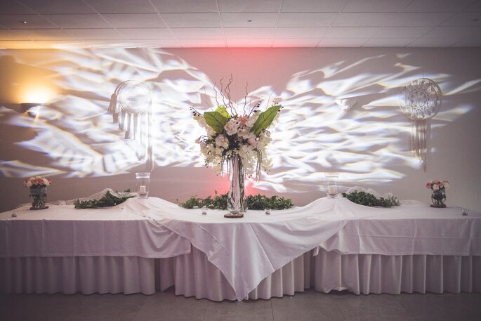Une décoration de mariage avec un grand bouquet central et des jeux de lumières 