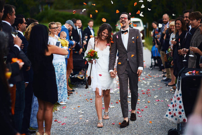 Ein Brautpaar läuft durch eine Menschenmenge in Blütenregen.