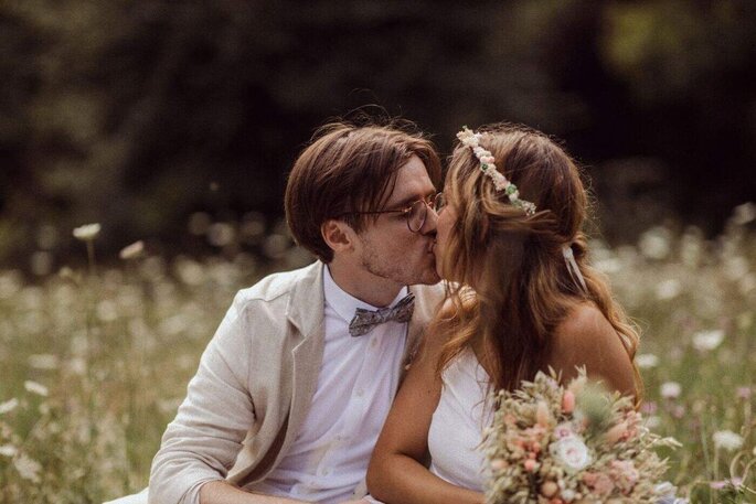 les mariés s'embrassent assis dans les champs de fleurs