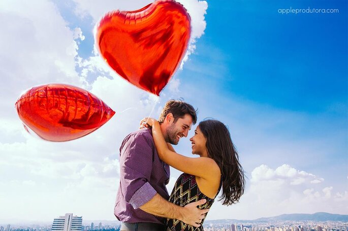 Casal abraçado com balões de coração vermelhos 