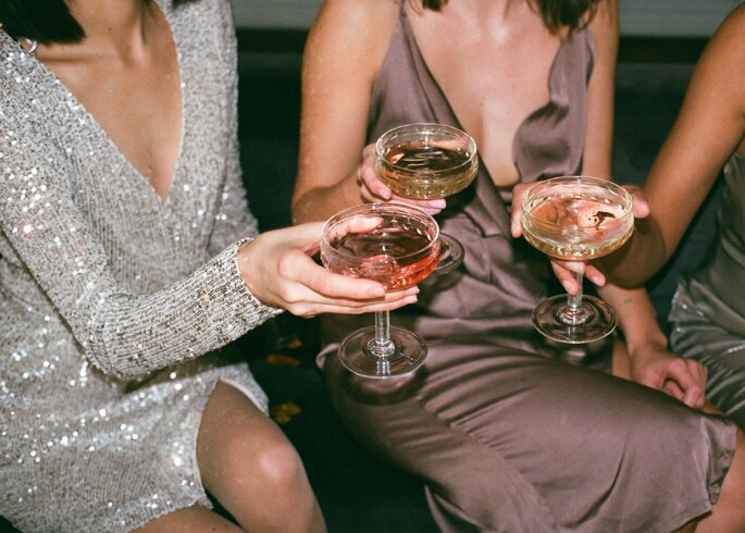 Kobiety w koktajlowych sukienkach popijają szampana