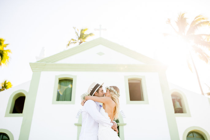 Casal de Noivos se beijando em frente a capela