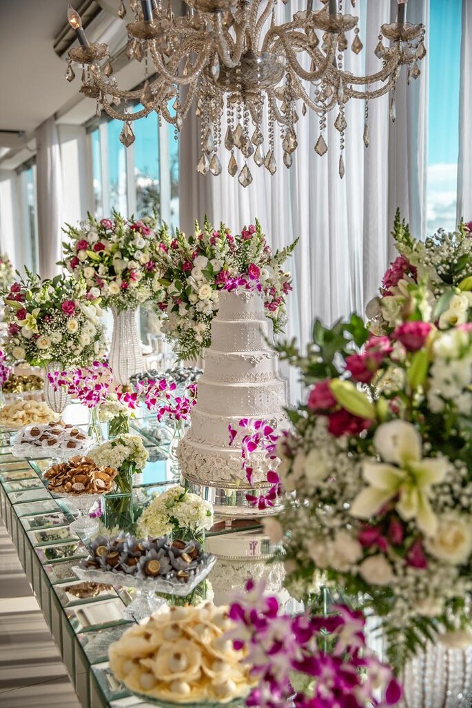 mesa decorada com flores, doces e bolo de casamento