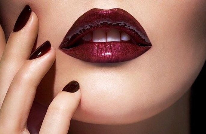 Labios pintados con un labial de color rojo intenso y uñas del mismo tono