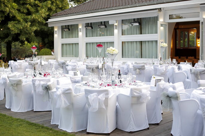 des tables et chaises blanches dressées en extérieur devant un lieu de réception