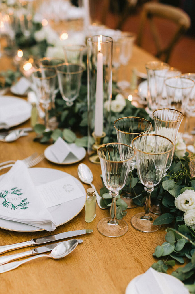 Table dressées pour un mariage avec un chandelier, des verres à bordure dorée et une décoration champêtre 