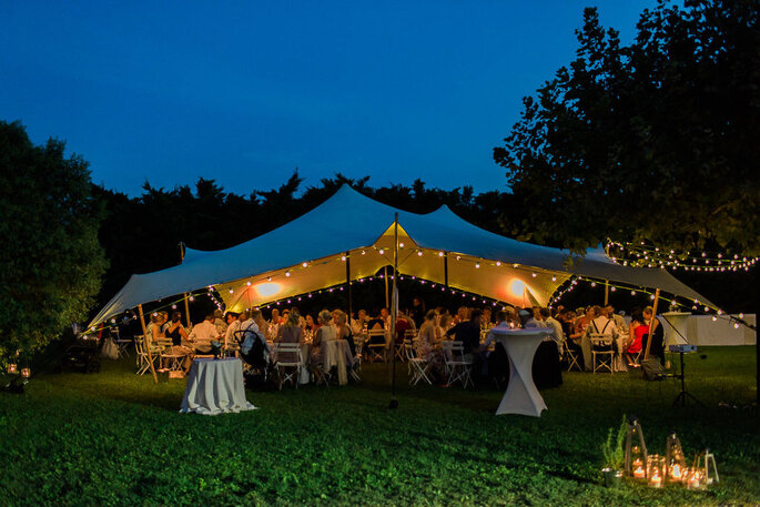 un dîner de mariage sous une tente de location, en plein air, avec des guirlandes guinguettes - La Bastide des Barattes 