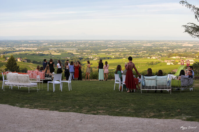 Les invités d'un mariage installés confortablement dans un parc avec une superbe vue sur le Beaujolais