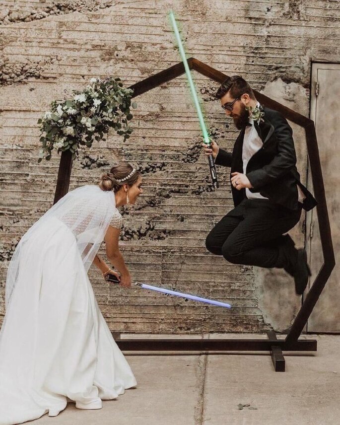 Recién casados posando con espadas de Guerra de las Galaxias