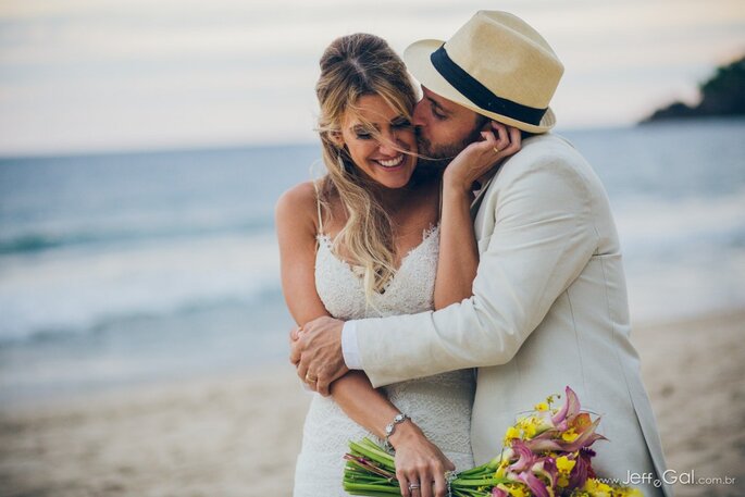 noivos se beijam em praia após o casamento 