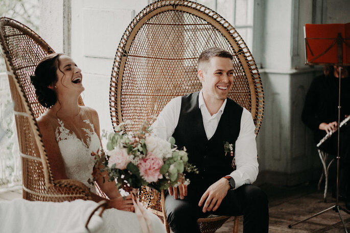 Ma petite cérémonie - Deux mariés en train de rire, assis sur des fauteuils en osier 