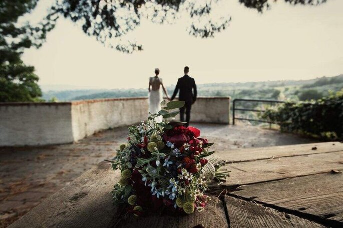 Fotomoderna Grillo bouquet in prrimo piano su tavolo, sposi sfocati su sfondo di spalle