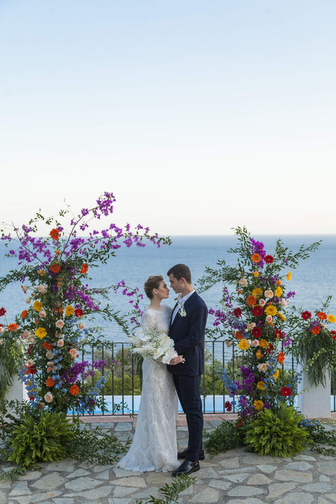 sposi con arco di fiori