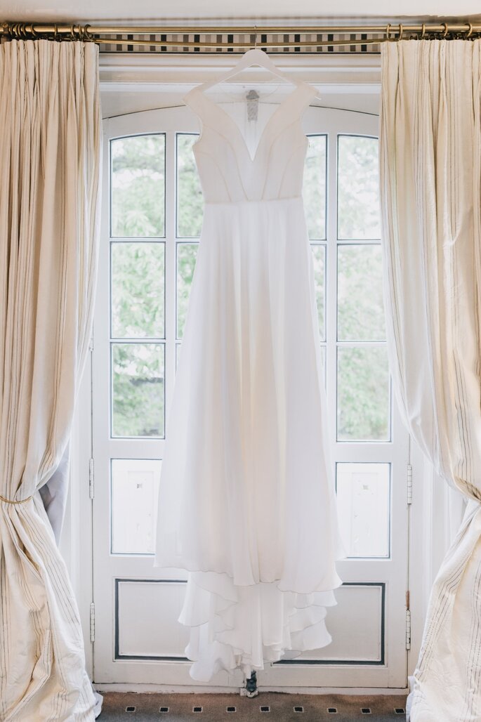 Une robe de mariée pendue à une tringle à rideaux 