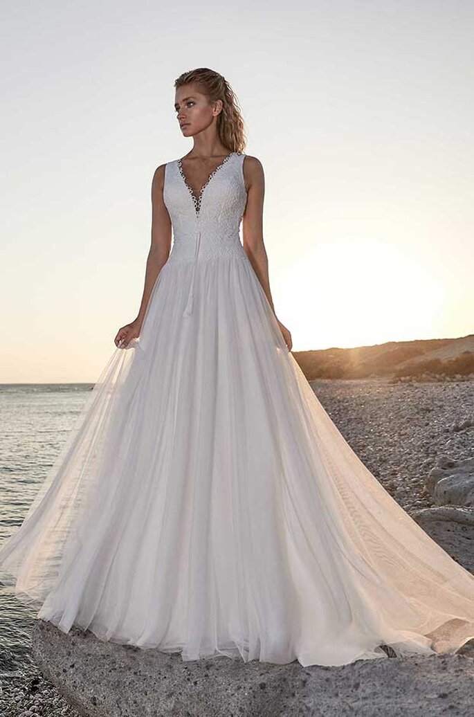 Eine Braut in einem eleganten Brautkleid mit V-Ausschnitt am Strand.
