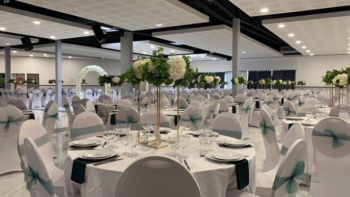 Tables blanches dressées avec centre de table fleuri pour un mariage au lieu de réception Les Salons du Grand Paris dans le Val de Marne