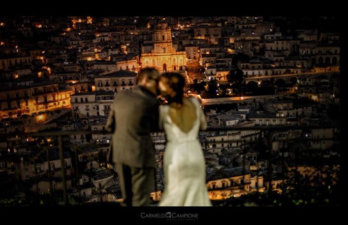sposi che si baciano, sfuocati, in primo piano Catania sullo sfondo