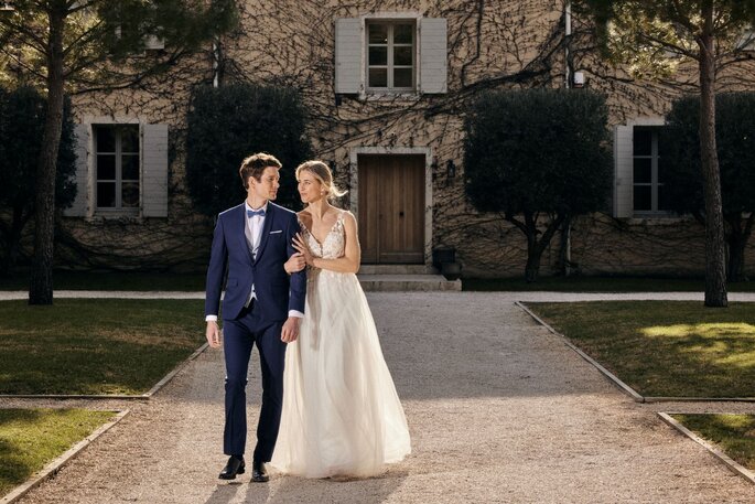 costume bleu pour mariage au bras de son épouse en robe blanche