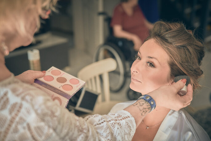Une maquilleuse est en train de réaliser le make up d'une future mariée