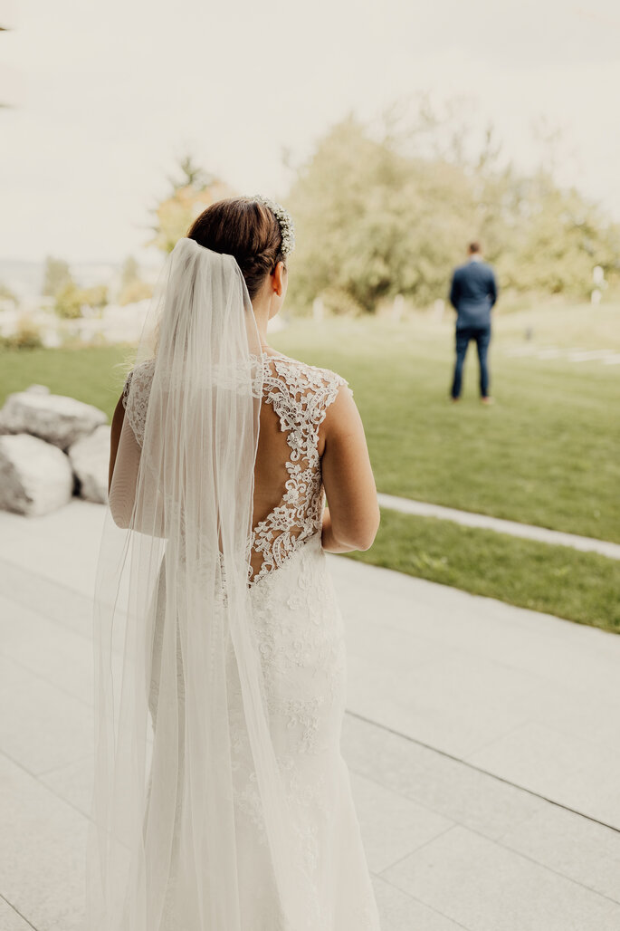 Brautkleid mit Rückenausschnitt. Braut von hinten zu sehen. Ihr gegenüber mit Rücken zu ihr der Bräutigam