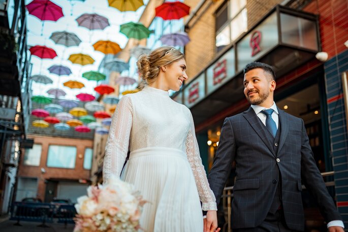 Un couple de mariés sous une allée de parapluies multicolore - Lisa Chonier Photographe 