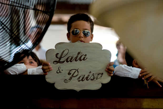 Niño con gafas sostiene letrero en madera con nombres tallados