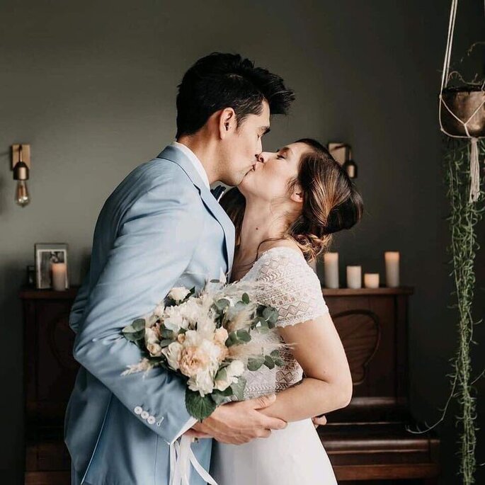 Un couple se donnent un baiser pendant que la mariée tient un bouquet de fleurs à la main, réalisé par Amaranthe