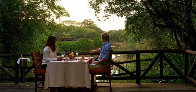casal a tomar uma refeição num terraço junto a um rio