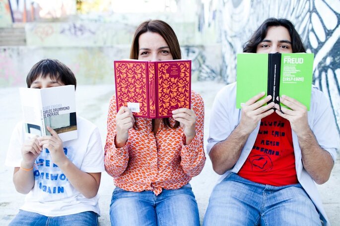 3 pessoas segurando livros coloridos