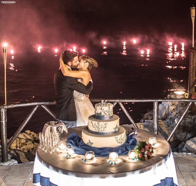 sposi si baciano davanti alla torta